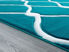 a blue rug with white lines on the top and bottom, in front of a wooden floor