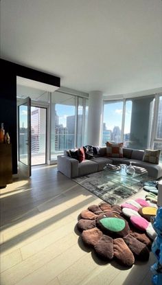 a living room filled with lots of furniture and large windows overlooking the cityscape