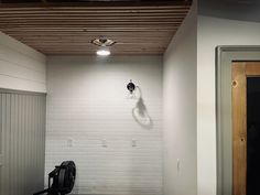 an empty room with a black backpack on the floor and a white brick wall behind it