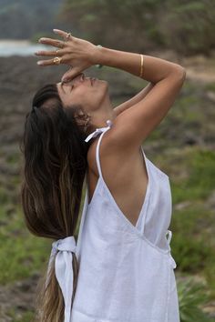 a woman with her hands up in the air while wearing a white shirt and gold bracelets