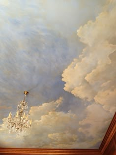 a chandelier hanging from the ceiling in a room with clouds painted on it