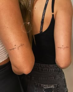 two women standing next to each other with tattoos on their arms and back, one has her arm wrapped around the other's shoulder