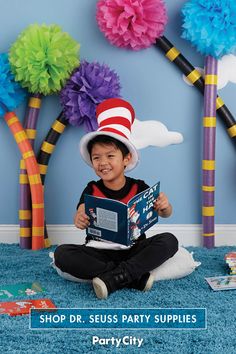 a little boy sitting on the floor reading a book wearing a cat in the hat