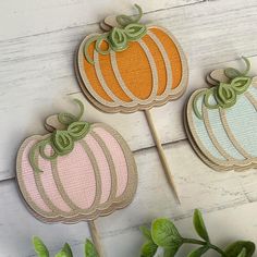 three pumpkin shaped cake toppers sitting next to each other on a white wooden surface