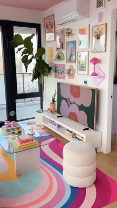 a living room filled with lots of colorful furniture and art on the wall next to a large window