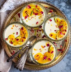 four glasses filled with pudding on top of a silver plate