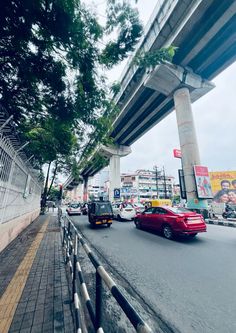 cars are driving down the street under a bridge