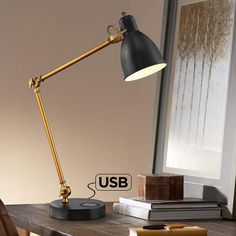 a desk lamp sitting on top of a wooden table next to a book shelf and window