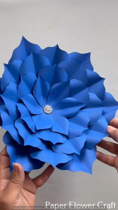 someone is holding up a blue paper flower