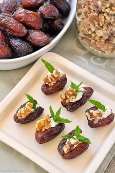 figs with goat cheese, walnuts and mint on a white plate next to a bowl of raisins