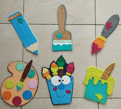 colorful wooden cut outs with paintbrushes, paints and brushes on the tile floor