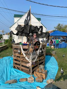 a man standing on top of a boat made out of wood pallets and tarp