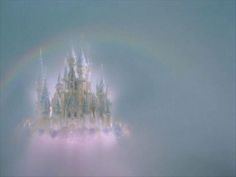 a castle with a rainbow in the middle of it's roof is seen through fog