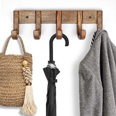 a coat rack with an umbrella hanging from it's hooks and two coats on the hangers