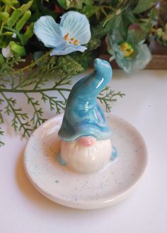 a blue and white figurine sitting on top of a plate next to flowers