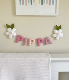 a pink and white sign that says pippa hanging from the side of a bed