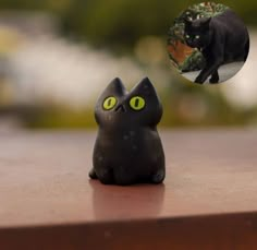 a black cat figurine sitting on top of a wooden table next to a green eyes