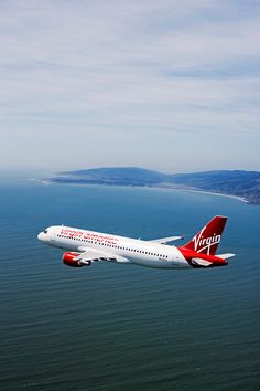 an airplane flying over the ocean on a clear day with blue sky and water in the background