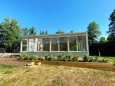 a small house sitting on top of a grass covered field next to trees and bushes