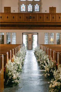 the aisle is lined with flowers and pews