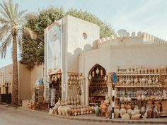 an outdoor market with lots of pots and vases on display in front of a building