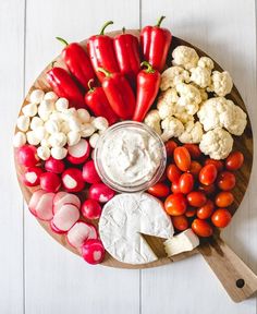 a wooden platter filled with vegetables and dip