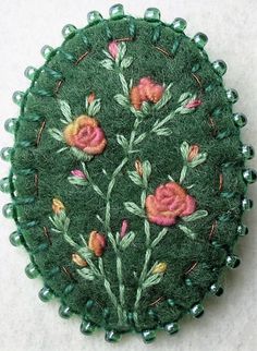 a green brooch with pink flowers on it