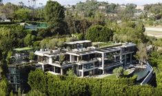 an aerial view of a large house surrounded by trees and bushes in the foreground