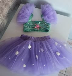 two pieces of purple and green tutule with starfish decorations on them sitting on top of a white table