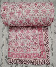 two pink and white bedspreads on top of each other