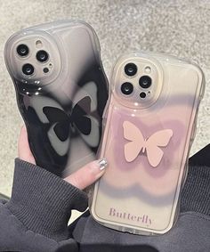 two cases with butterflies on them are held up by someone's hand in front of the camera