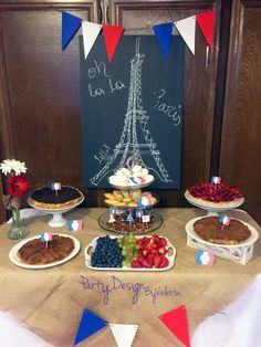 a table topped with cakes and desserts next to a chalkboard sign that says paris