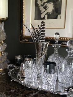 a table topped with lots of glassware and a painting on the wall behind it