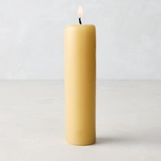 a yellow candle sitting on top of a white table