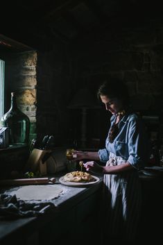 a woman standing in front of a counter preparing food