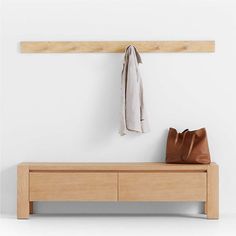 a wooden bench with a coat rack and purse on it next to a white wall