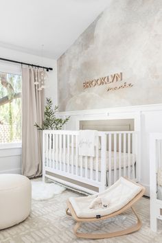 a baby's room with a white crib, rocking chair and large window