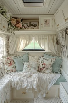 a white couch sitting under a window next to a bed in a room with lots of pillows