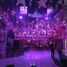 people are standing in the middle of a room with stars hanging from the ceiling