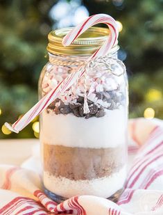 a glass jar filled with candy canes and marshmallows next to a christmas tree