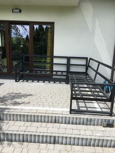 a black metal bench sitting on top of a stone floor next to a door and steps