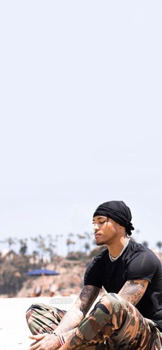 a man sitting on the beach with his legs crossed