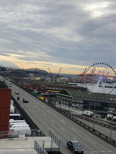 an aerial view of a city with ferris wheel in the distance and cars driving down the road