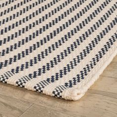 a white and blue rug on the floor with wood floors in the background, close up