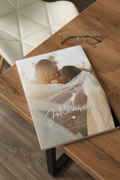 an image of a wedding album on a table next to a pair of eyeglasses