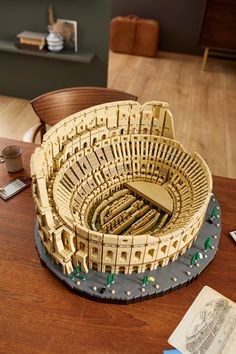 a model of a roman colossure on top of a wooden table next to an open book