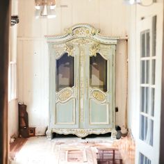 an antique armoire in the corner of a room that is being renovated with white paint and gold trim