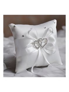 a white pillow with a bow and diamond heart on the front, sitting on a bed