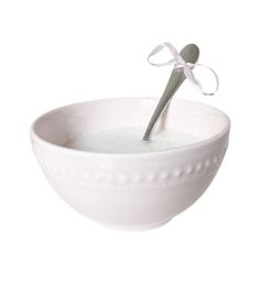 a white bowl filled with water and a spoon sticking out of the top, on a white background