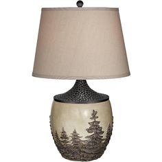 a lamp that is sitting on top of a table next to a lamp shade with trees painted on it